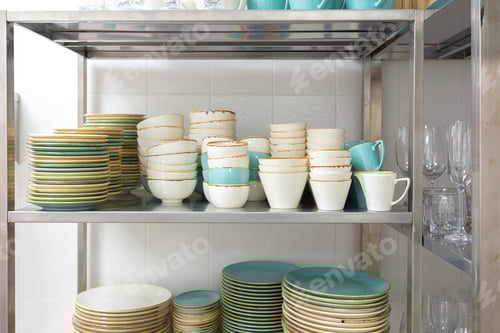 Preview: Stacked dishware and glassware on a stainless steel shelf in a kitchen setting