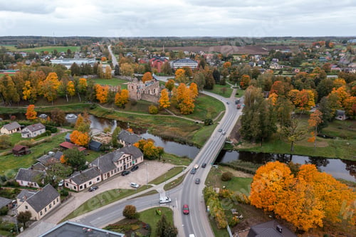 Preview: Aerial view of a quaint town with autumn foliage and historical ruins in the background
