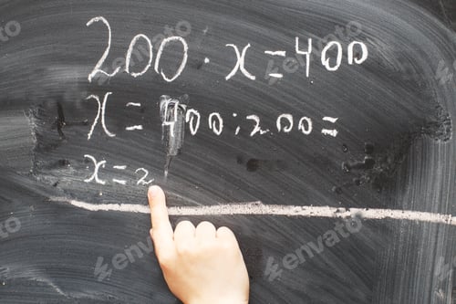Preview: Boy standing back in front of school blackboard and writing.