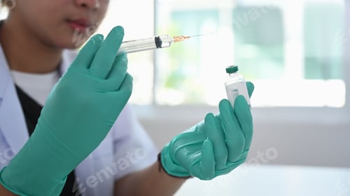 Preview: Close up view of female doctor holds syringe and bottle with vaccine.