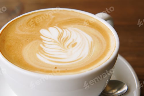 Preview: a cup of late coffee with flower shape design on top at cafe