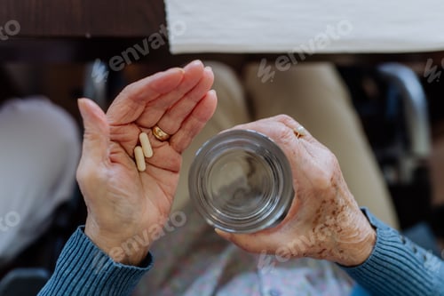 Preview: High angle view of senior woman taking pills.