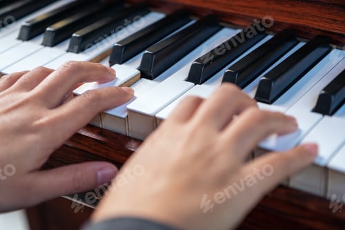 Preview: Closeup image of hands playing a vintage wooden grand piano