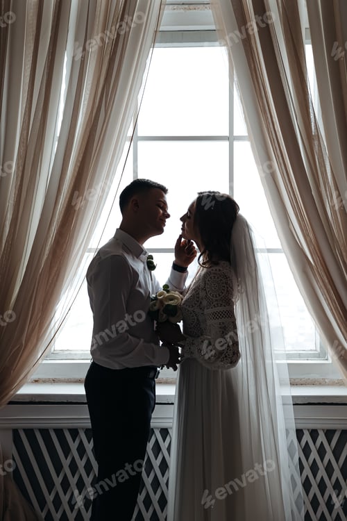 Preview: The bride and groom are posing tenderly near the window.
