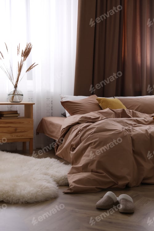 Vorschau: Bett mit brauner Bettwäsche in stilvollem Zimmerinterieur