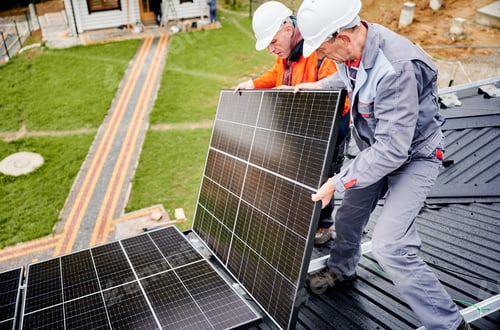 Preview: Technicians carrying photovoltaic solar module while installing solar panel system on roof of house