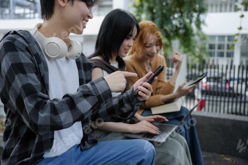 Preview: Three young people smiling and using electronic devices for learning