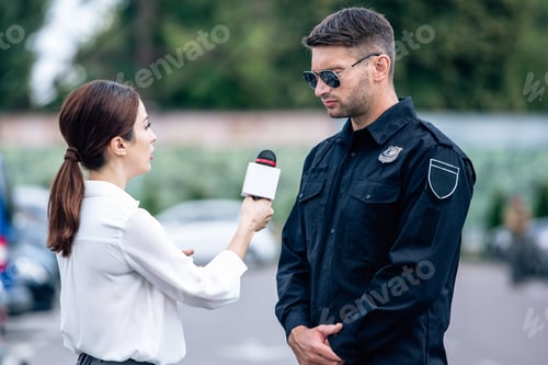 Preview: journalist holding microphone and talking with handsome policeman in uniform