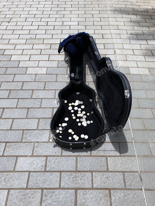 Preview: Collection of coins inside an open guitar case on ground