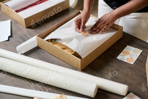 Preview: Hands of young black woman putting sticker on top of wrapping paper