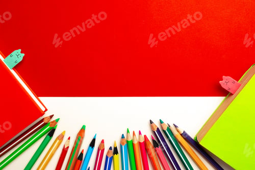 Preview: Colorful pencils and notepads on paper background top view