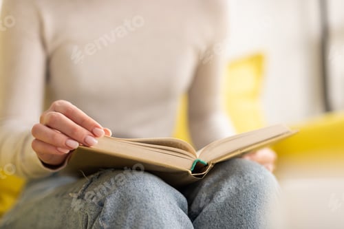 Preview: Cropped view of woman reading book on sofa at home