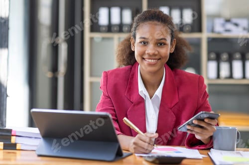Preview: Smiling young woman sitting on chair holding mobile phone using cellphone device, looking at phone,