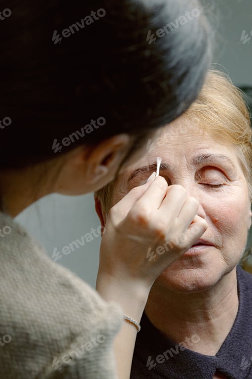 Preview: A cosmetologist paints the eyebrows of an elderly woman.