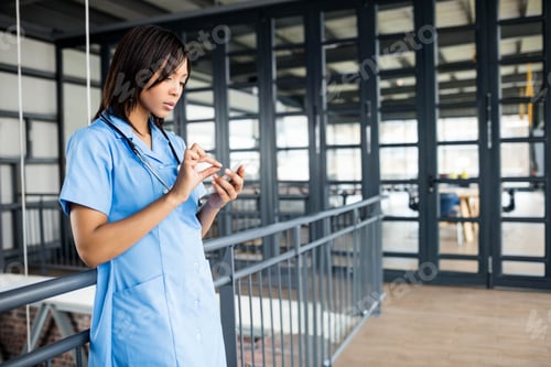 Preview: Smartphone leaning against metal railing on mezzanine with stethoscope by glass desks and chairs