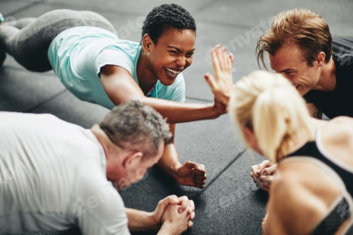 Preview: Two laughing women high fiving while planking at the gym