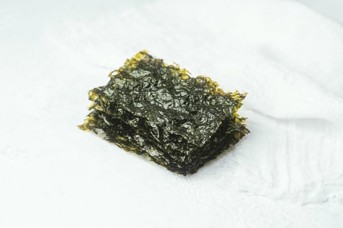 Preview: Crispy seaweed snack in white bowl with loose piece on light background