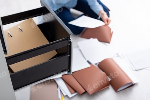 Preview: Selective focus of businesswoman with documents near open cabinet driver sitting on floor
