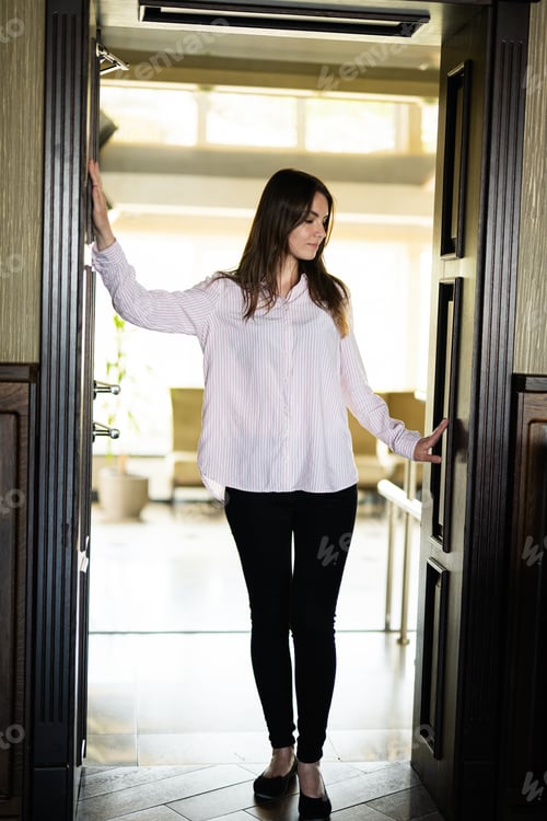 Preview: Young beautiful brunette woman standing in the doorway.