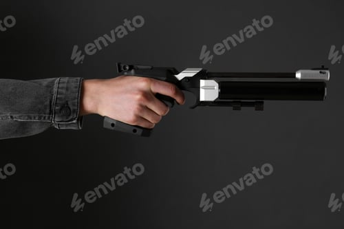 Preview: Gun shooting sport. Man aiming standard pistol on dark background, closeup