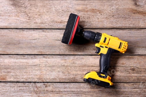 Preview: Electric screwdriver with polish pad on wooden table, top view. Space for text