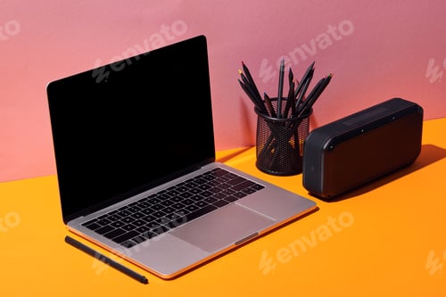 Preview: cropped view of woman using laptop with blank screen near pencil holder and speaker