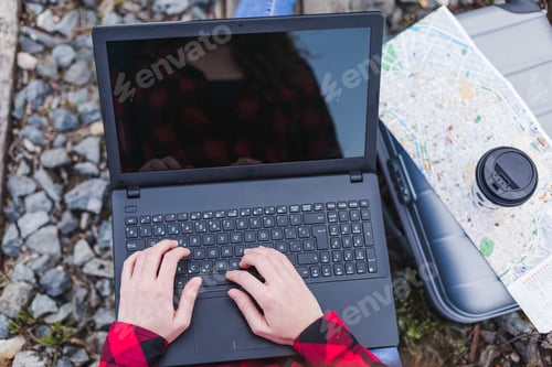 Preview: woman sitting on railing working on laptop outdoors