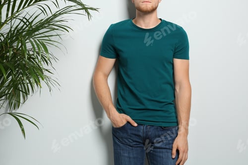 Preview: Young man wearing blank t-shirt on light background, closeup. Mockup for design
