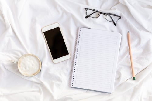 Preview: Notebook, phone, glasses, coffe.Home office on bed with white sheets. Mockup card.
