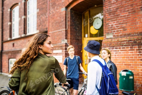 Preview: Friends chatting by a brick building after a bike ride.