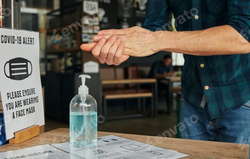 Preview: Man rubbing hands together using hand sanitiser in restaurant