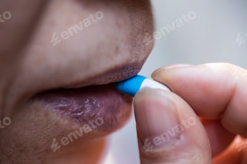 Preview: Closeup shot of a person swallowing a blue and white pill