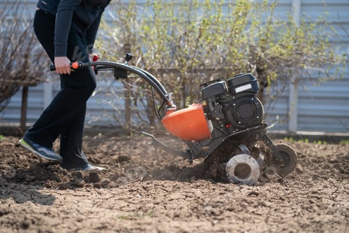 Preview: a young man digs the ground in the garden with a motor-cultivator