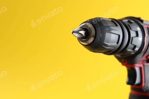 Aperçu: Modern electric screwdriver on yellow background, closeup. Space for text