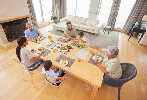 Preview: Overhead view of a mixed race family sitting at a table having lunch in the lounge at home. Hispan