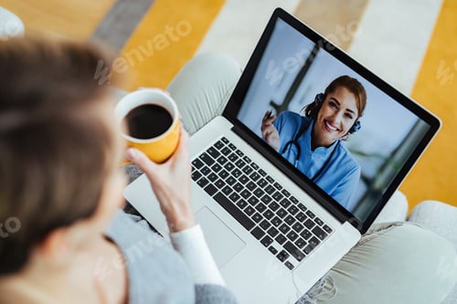 Preview: Young happy doctor having video call with patient who is calling her from home.