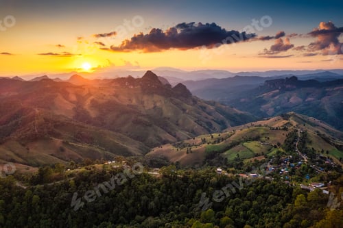 Preview: Rural landscape of sunset over rolling mountain with local village in the valley