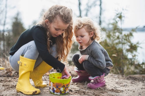 Preview: Two young children enjoying playtime outdoors by the lake.