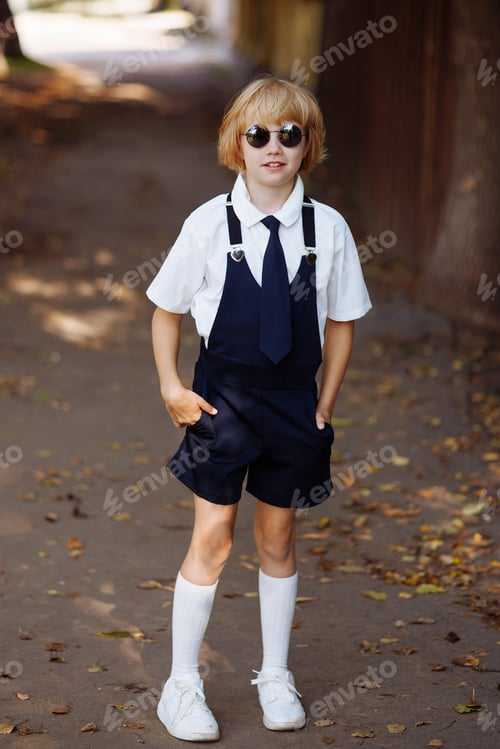 Preview: Portrait of a young schoolgirl in black round sunglasses and school uniform. Back to school.