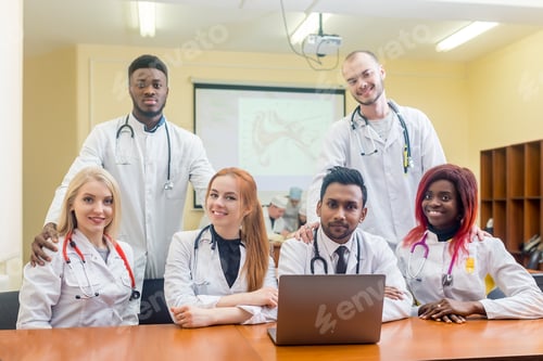 Preview: Multiracial team of young doctors working on laptop computer in medical office