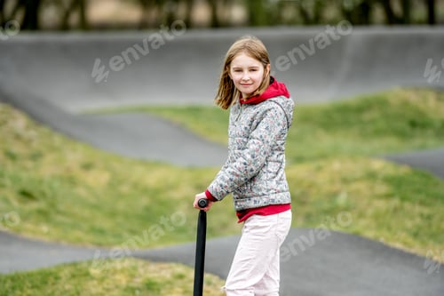 Preview: Beautiful little girl rides a scooter in a extreme ride park