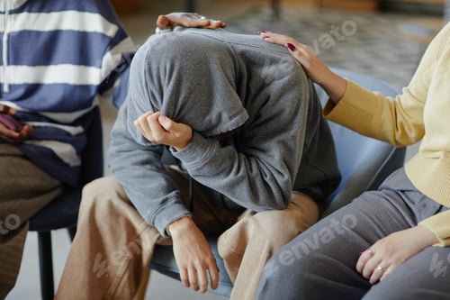 Preview: Teenager Hiding Face in Hands While Receiving Comfort from Support Group