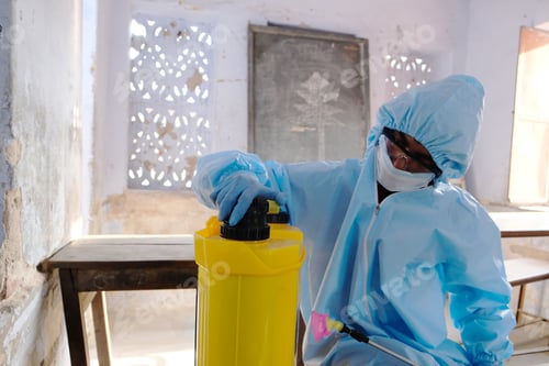 Preview: Indian sanitary worker in a protective suit conducting disinfection of a school during COVID-19