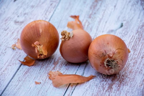 Preview: Brown onions on a wooden table background