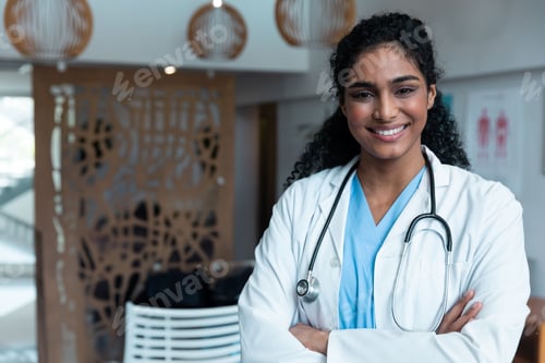 Preview: Female doctor standing in clinic lobby, wearing lab coat and scrubs with stethoscope, copy space