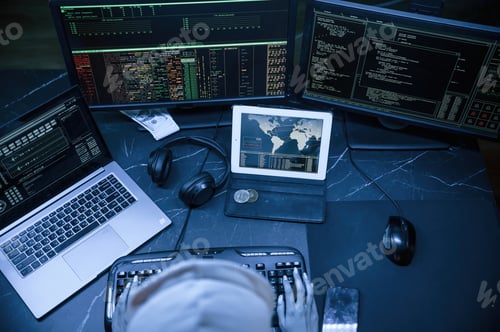Preview: Young professional female hacker is indoors by computer with lot of information on displays
