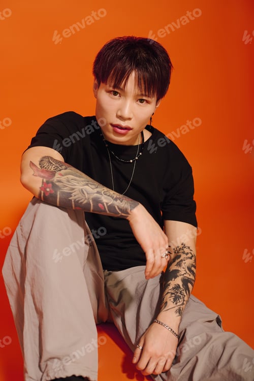 Preview: Handsome stylish asian man showcasing a modern look against a vibrant orange backdrop