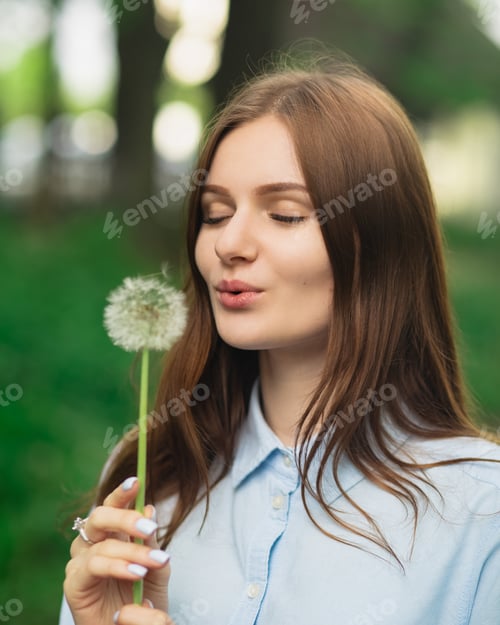 Preview: A Young Woman Holding a Dandelion Surrounded by a Lush, Lively Green Setting Providing Peace