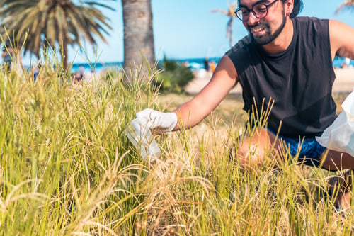 Preview: A happy activist is picking up trash in a field taking care of the environment