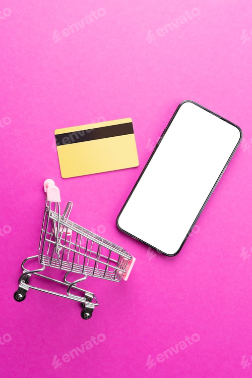 Preview: Composition of shopping cart, credit card and smartphone with copy space on pink background